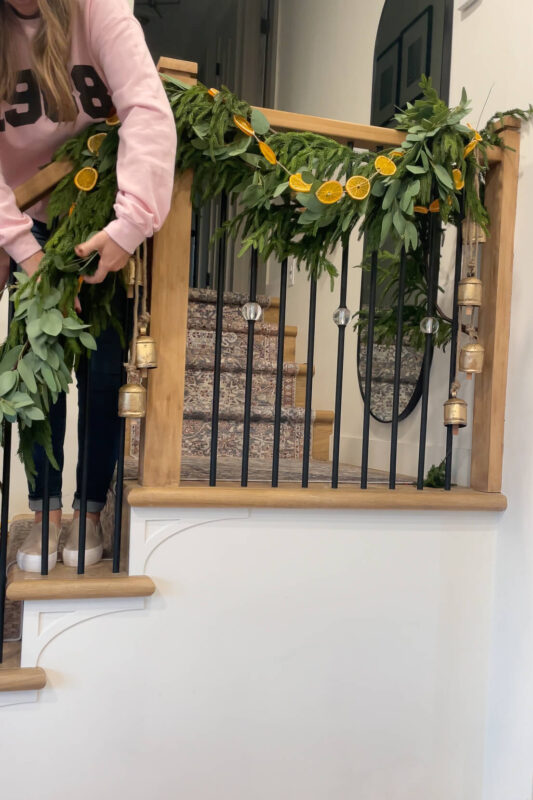 Wrapping an orange slice garland on a staircase.